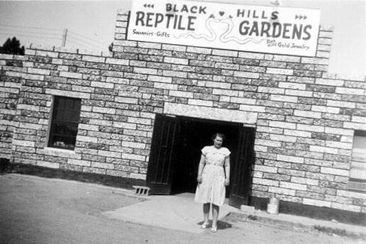 A historic black and white photo of a lady standing in front of the Black Hills Reptile Gardens entrance in 1937.